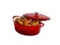 Cocotte en fonte rouge avec poulet et légumes, couvercle partiellement ouvert.