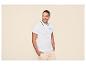 Homme en polo blanc à liseré noir et short cargo beige clair.