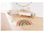 Une chambre d'enfant avec un tapis arc-en-ciel, une chaise et une boîte de rangement.