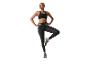 Femme en brassière de sport noire et leggings, en équilibre sur une jambe.