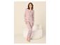 Femme en pyjama deux pièces rose clair, composé d'un pantalon long et d'un haut boutonné à manches longues.