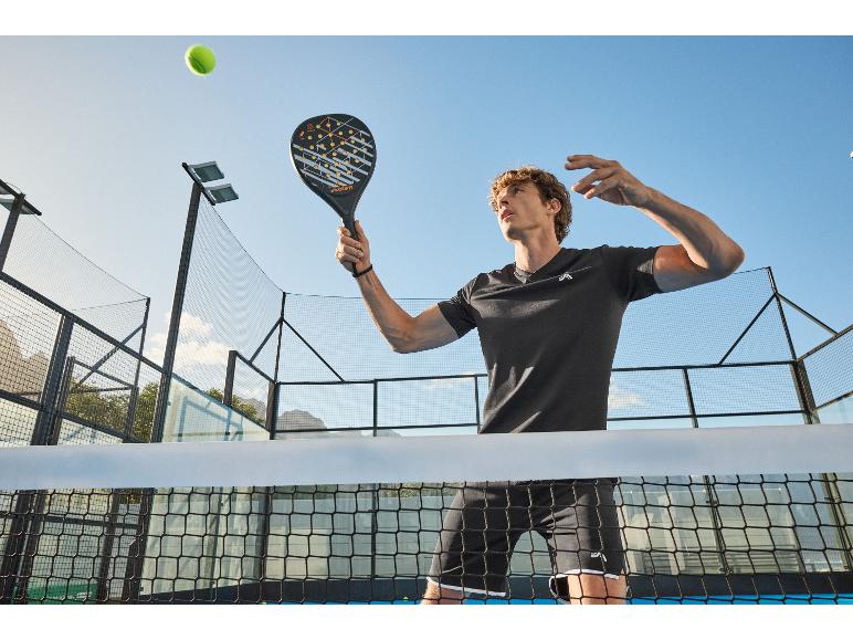 Homme jouant au padel, tenant une raquette de padel, avec une balle de tennis en l'air.