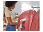 Une femme repasse une chemise avec un défroisseur vapeur.