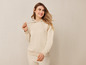 Une femme porte un sweat à capuche beige et un pantalon assorti.