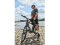 Homme à vélo près de l'eau avec une gourde à la main.