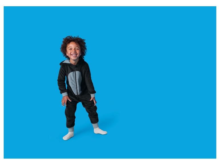 Un enfant souriant porte une combinaison noire moelleuse avec un ventre gris.