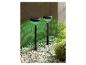 Deux lampes solaires de jardin noires avec lumière verte sur un chemin de gravier.