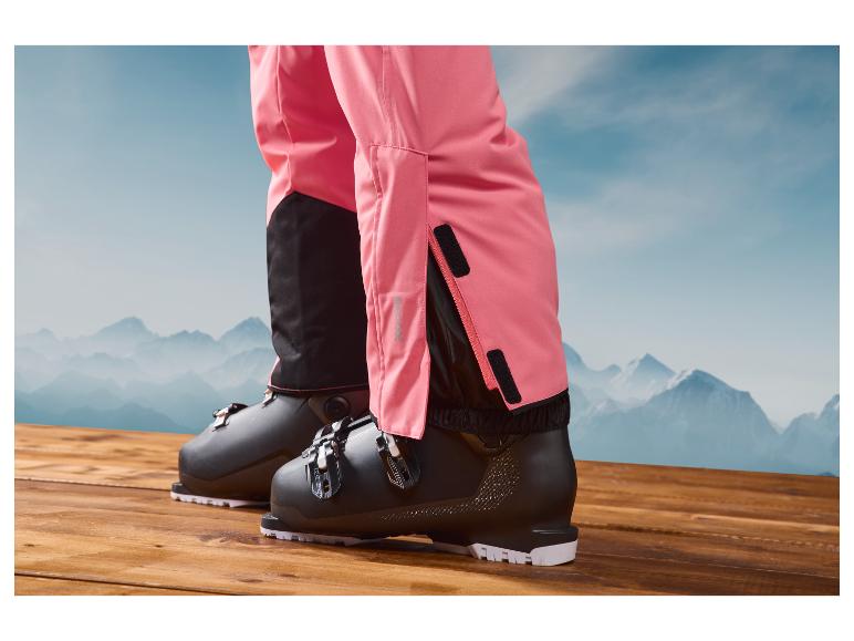 Des chaussures de ski et un pantalon de ski rose avec des réflecteurs Recco.