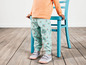 Un enfant portant un t-shirt rose et un pantalon bleu à imprimé floral.