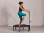 Une femme saute sur un trampoline avec une poignée.