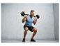 Un homme fait des squats avec une barre dans une salle de sport.