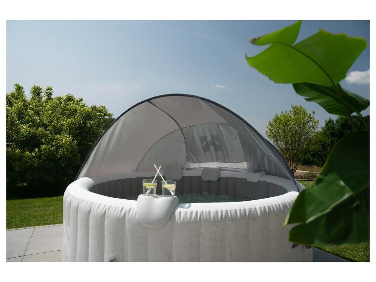 Spa gonflable avec auvent, deux boissons et fond de jardin verdoyant.