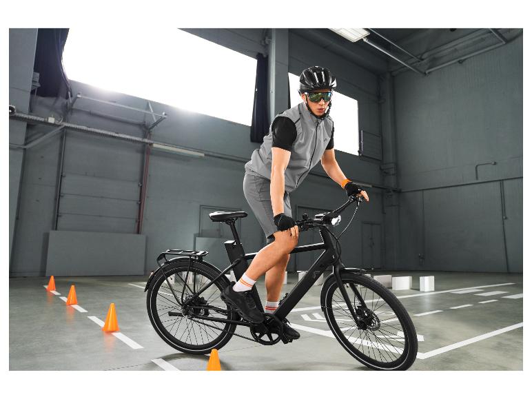 Homme en gilet réfléchissant et lunettes de cyclisme à vélo, s'entraînant entre des cônes.