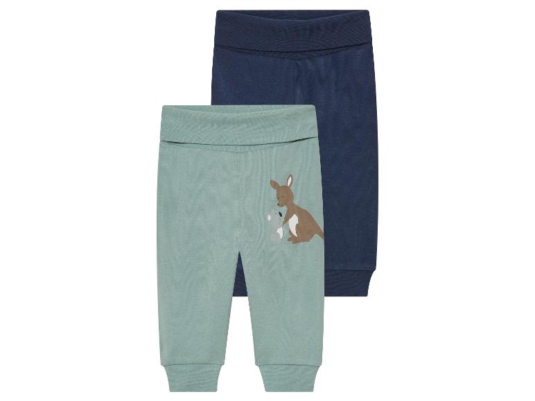 Deux pantalons bébé : un vert clair avec kangourou, un bleu marine uni.