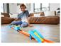 Un enfant joue avec une piste de course Hot Wheels et des voitures miniatures.