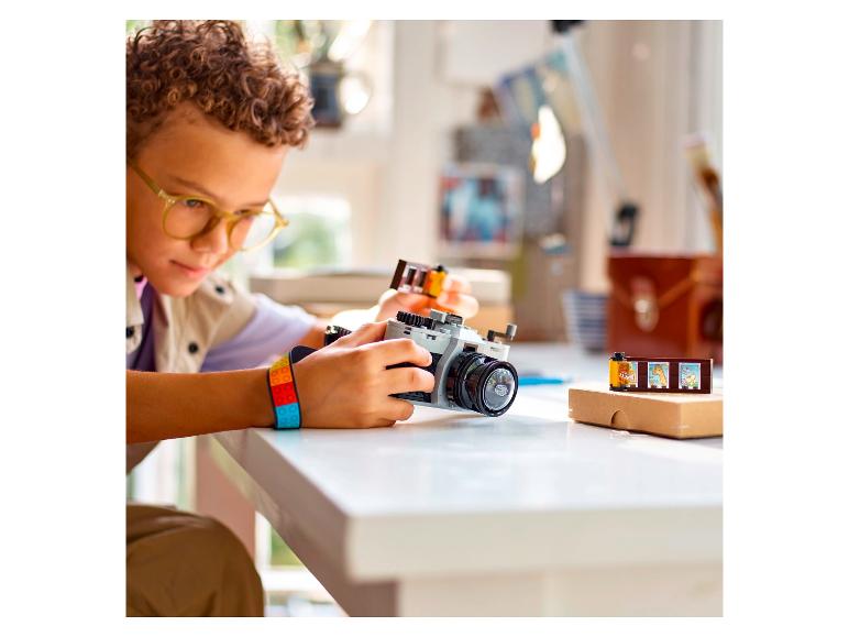 Un garçon jouant avec un set LEGO d'un appareil photo et des rouleaux de film.
