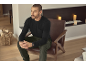Homme en t-shirt noir à manches longues et pantalon vert assis sur une chaise en cuir.