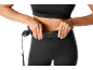Une femme met une ceinture de stimulation musculaire abdominale noire.