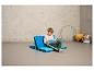 Un garçon assis sur un matelas bleu et turquoise en train de lire un livre.