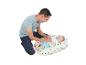 Un père joue joyeusement avec son bébé sur un coussin coloré.