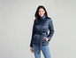 Une femme porte une veste matelassée bleu marine avec une ceinture.
