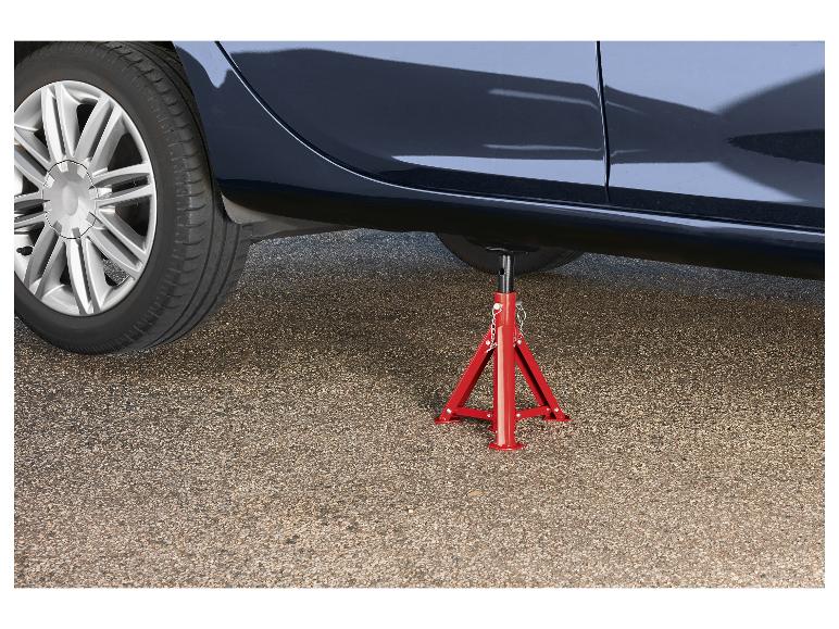 Une voiture soutenue par un cric rouge sur une surface asphaltée.