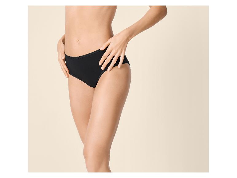 Femme en culotte de coton noire, posant les mains sur les hanches.