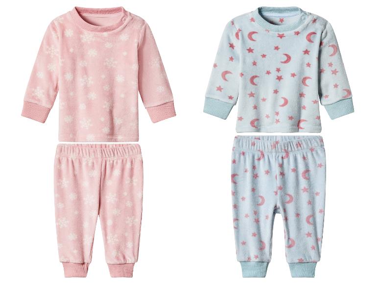 Deux ensembles de pyjamas pour bébé: rose avec flocons de neige et bleu avec lunes et étoiles.