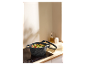 Une casserole en pierre noire avec des pâtes et des légumes sur une plaque à induction.