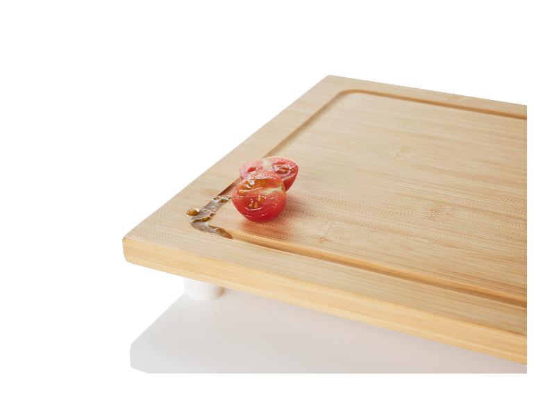 Une planche à découper en bambou avec deux moitiés de tomates.
