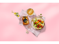 Pot de miel avec rayon, salade de fruits dans un melon et fleurs sur fond rose.