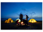 Un groupe de personnes campe sur la plage avec un feu de camp et des tentes.