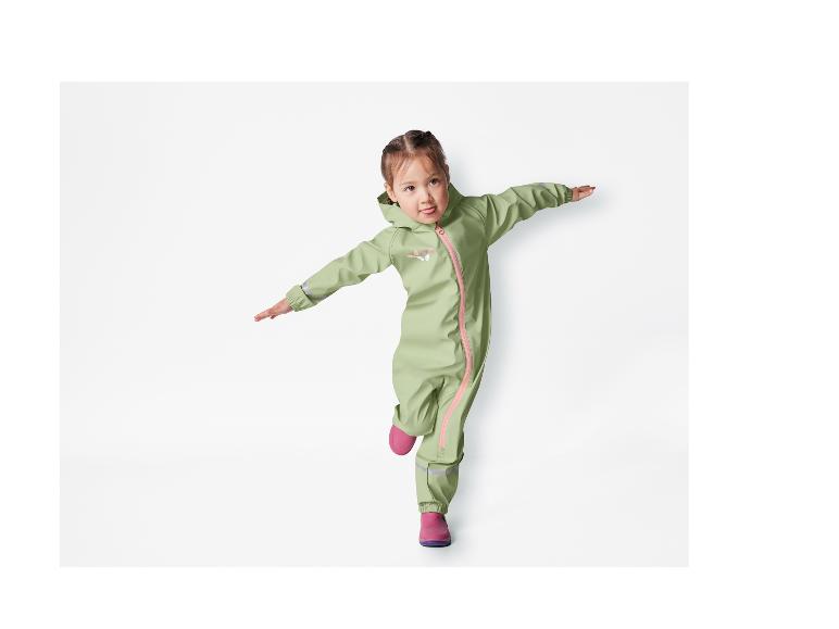 Une petite fille porte une salopette de pluie verte avec des papillons et des bottes roses.