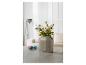 Un vase gris avec des fleurs sur une table avec des œufs à côté.