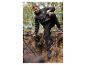Un homme porte une veste et un pantalon noirs de Mountain Warehouse dans une forêt.