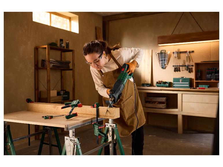 Femme dans un atelier coupant une poutre en bois avec la scie sabre PARKSIDE PFS 850 C3.