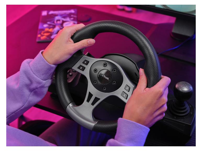 Mains tenant un volant de jeu avec levier de vitesse, sur un bureau éclairé en rose.