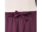 Pantalon en velours violet foncé avec cordon de serrage à la taille, combiné à un haut blanc côtelé.