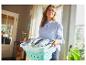 Une femme porte un panier à linge vers l'extérieur.