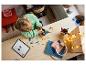Un enfant construit un robot LEGO sur une table en bois, avec une tablette affichant les instructions.