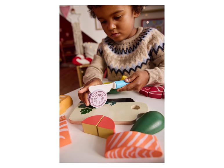 Enfant jouant avec des aliments jouets et une planche à découper.