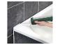 Une main appliquant du mastic silicone sur une baignoire.