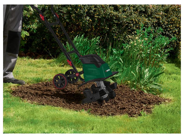 Personne utilisant un motoculteur électrique Parkside pour cultiver la terre dans un parterre.