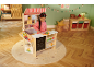 Fille jouant avec un magasin de jouets en bois, décoré dans un style de Noël.