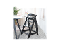 Chaise haute en bois noir avec plateau et harnais de sécurité à côté d'une table blanche.
