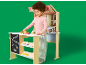 Enfant jouant avec un stand de jouets en bois avec des fruits et légumes.