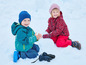 Deux enfants en vêtements d'hiver jouent dans la neige.