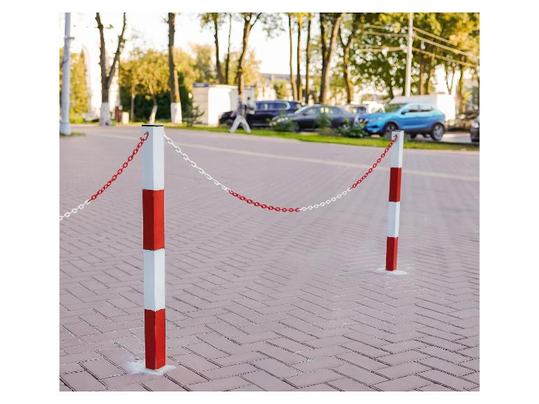 Poteaux de barrière rouges et blancs avec chaîne dans une rue avec des voitures garées.
