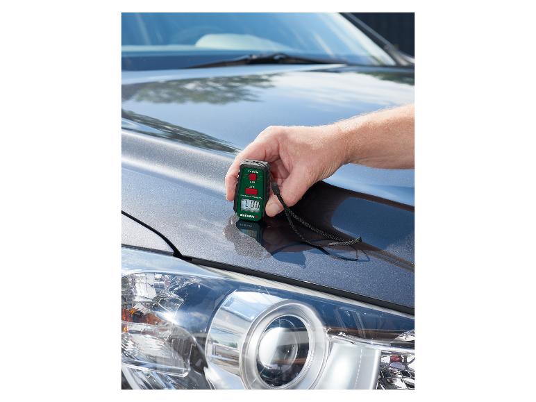 Un homme utilise un appareil de mesure d'épaisseur de peinture PARKSIDE sur le capot d'une voiture.