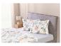 Un lit avec une couette blanche à motifs de feuilles vertes et deux oreillers assortis.